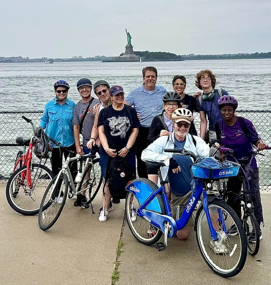 Several members of Madison Avenue Baptist Church posing in front of the Statue of Liberty with their bikes