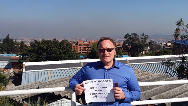 Church member holding an MABC sign on a bridge overlooking Bogotá, Colombia
